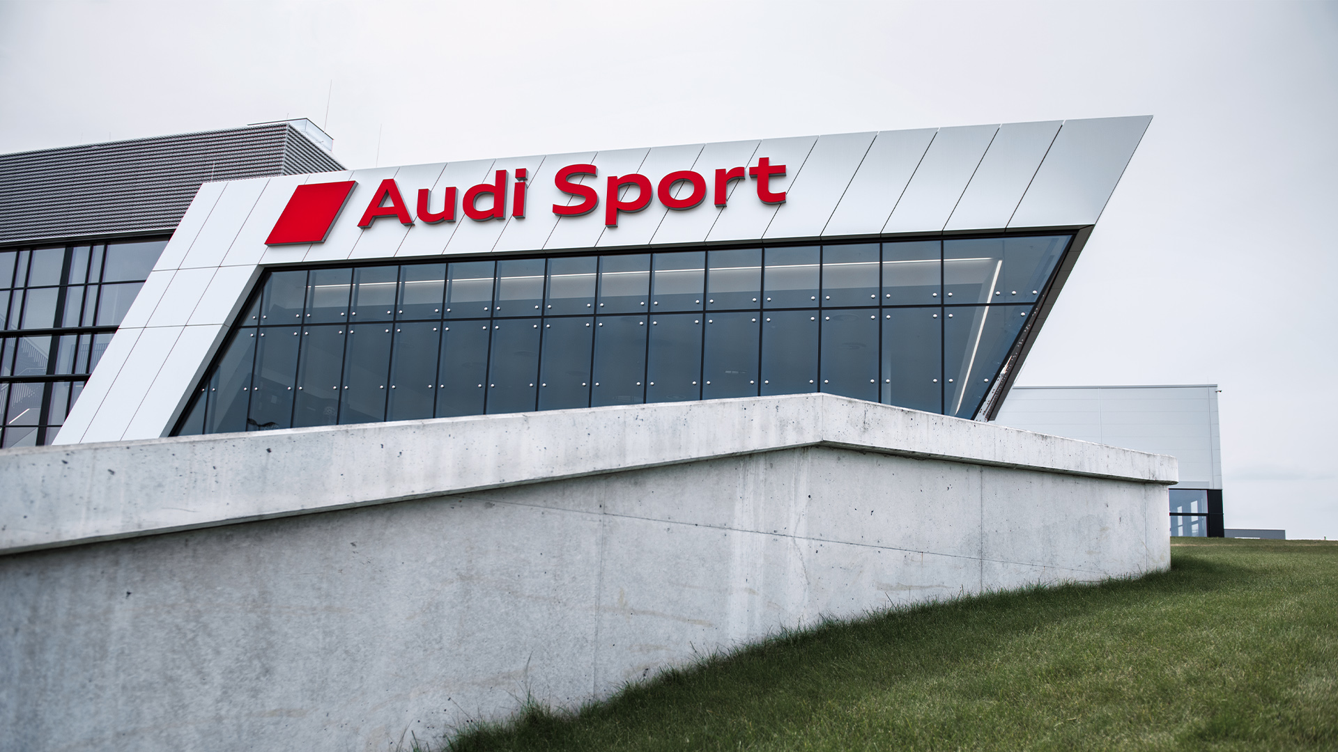 Dietro un muretto si vede l'edificio di Audi Sport.