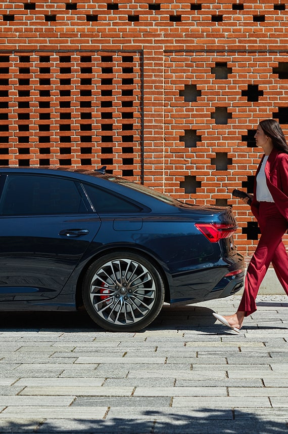  Una donna cammina a fianco di Audi A6 Avant TFSI e